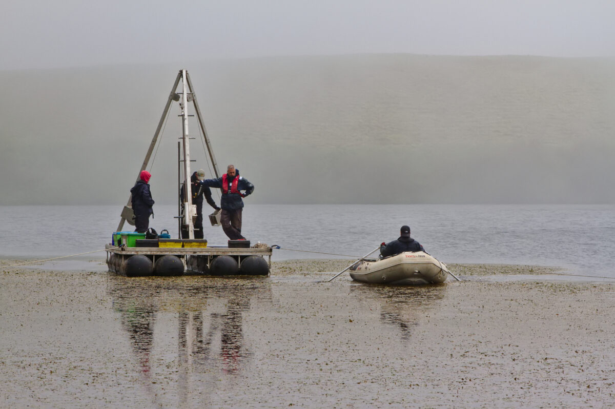 Toma de muestras en el lago Lomba donde se aprecia el crecimiento de plantas en la superficie (Santiago Giralt).